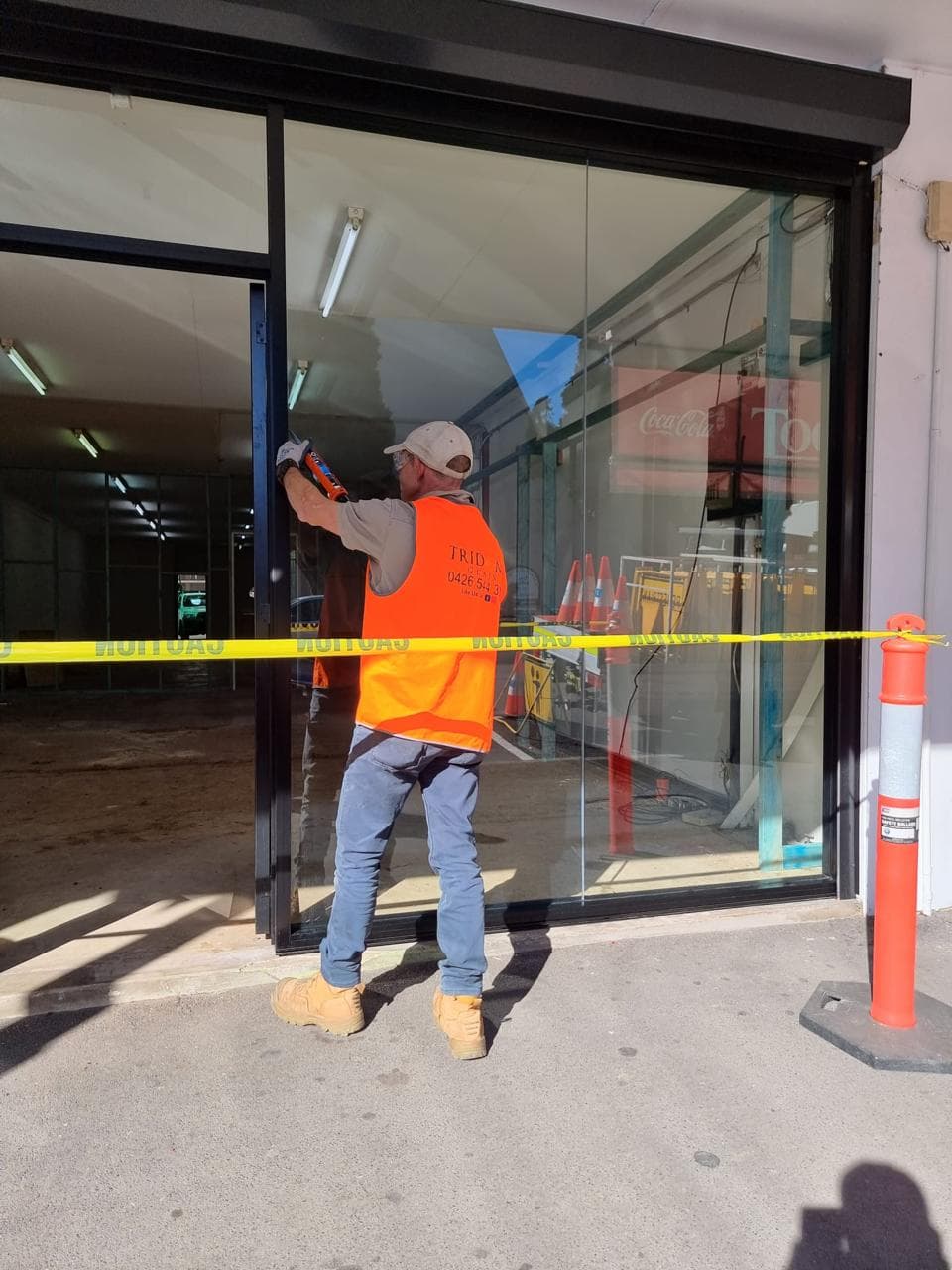 Glaziers fitting frameless glass shopfront panels — Sydney Shop Fronts installation team on site