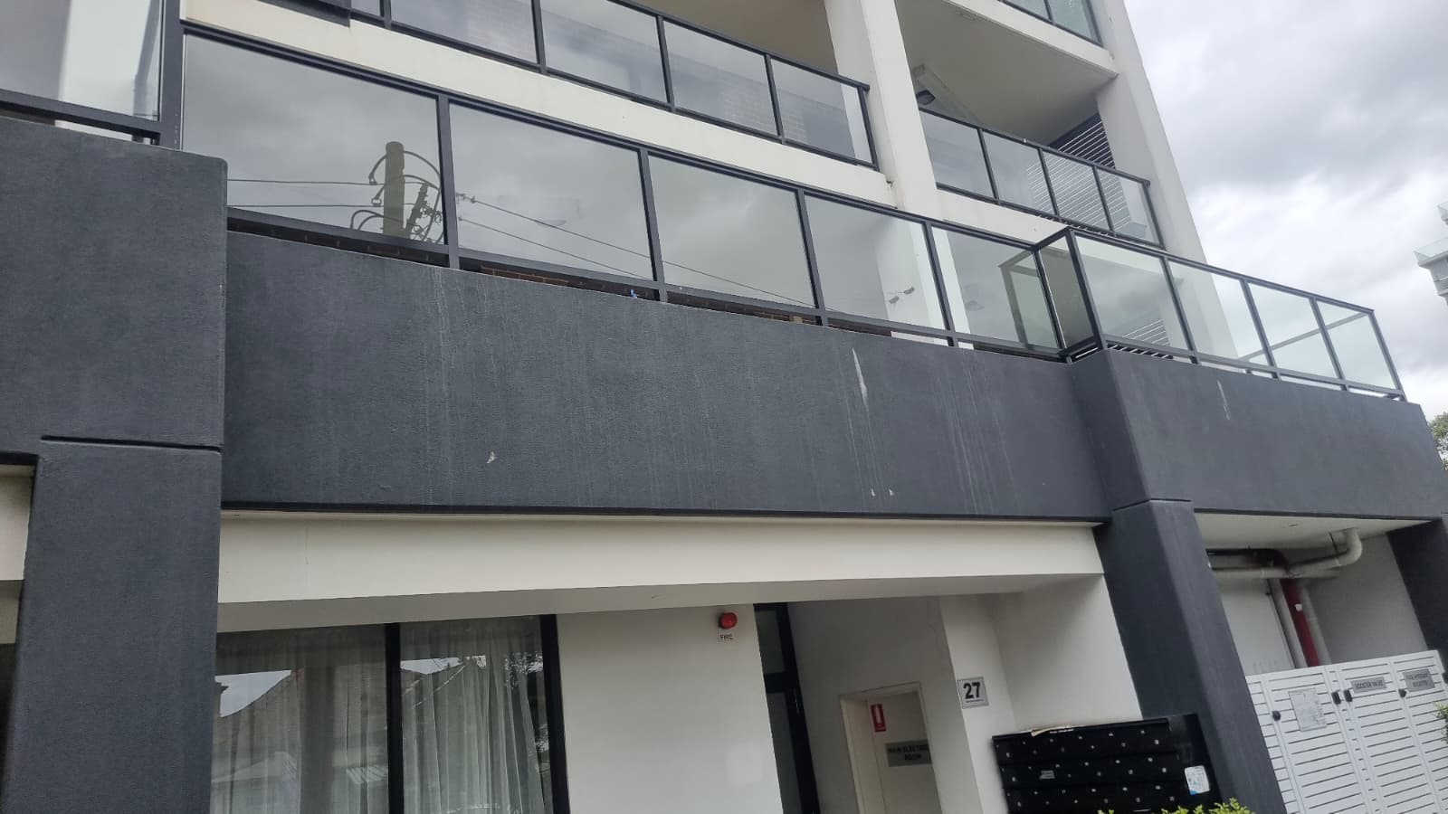 External view of modern apartment building with frameless glass balustrade and black aluminium railing