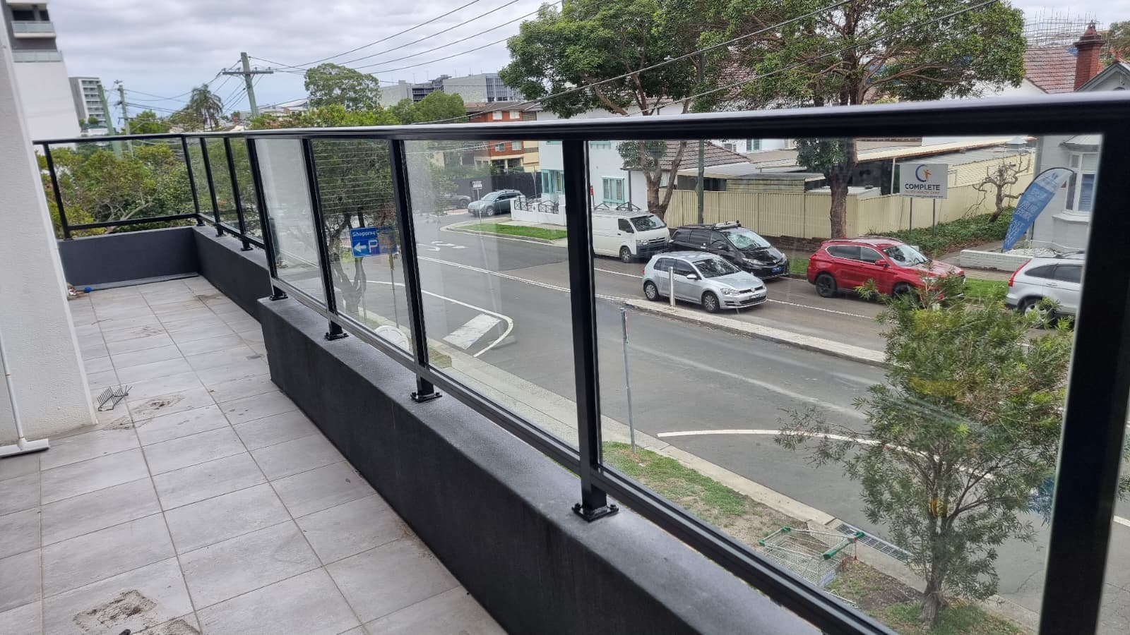 Side balcony view with frameless glass balustrade and black aluminium handrail overlooking street