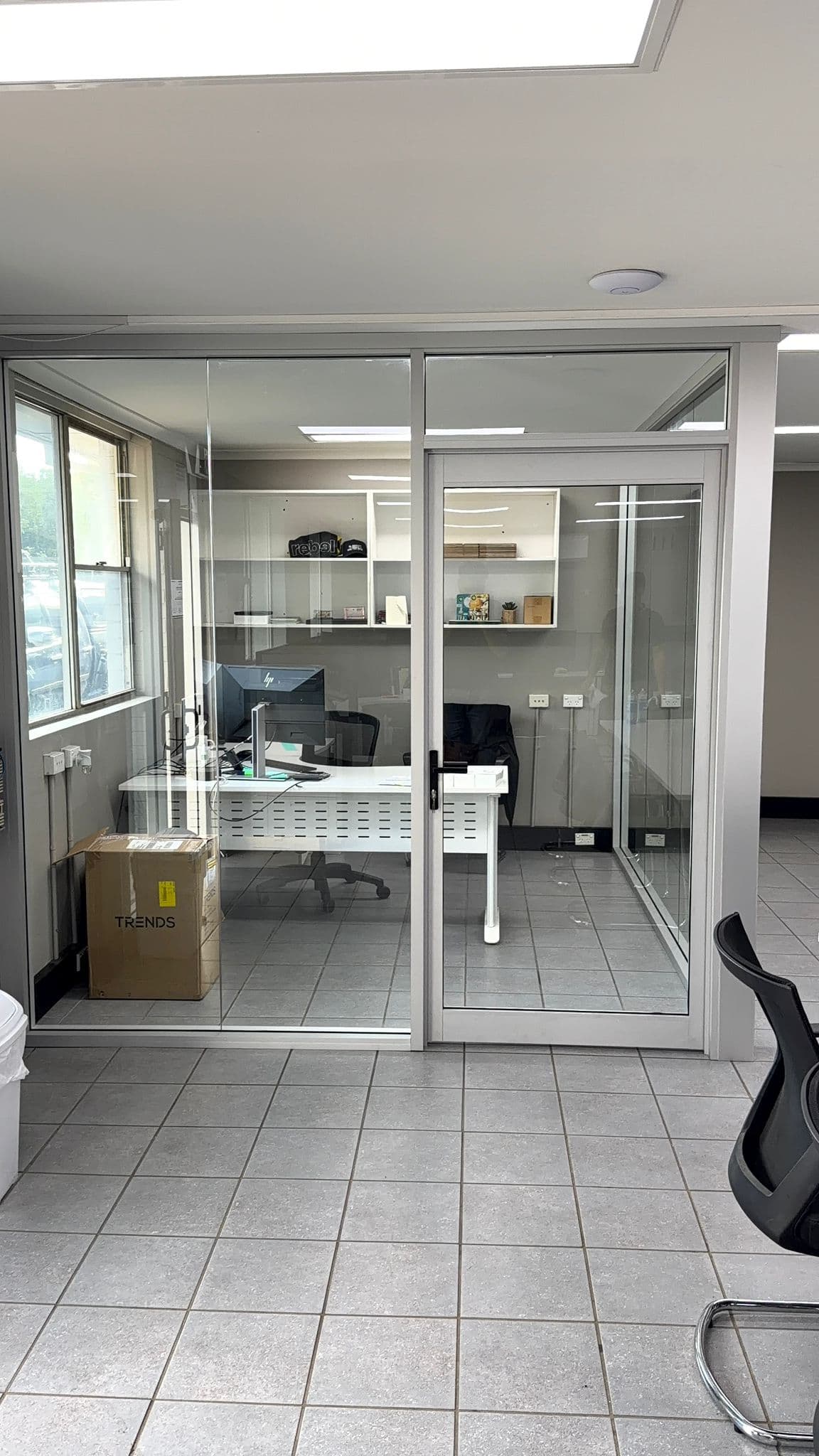 Commercial office glass partition installation with framed glass door and workspace enclosure