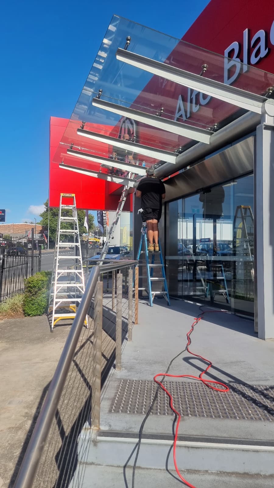 Finished frameless glass awning installation for commercial storefront entrance